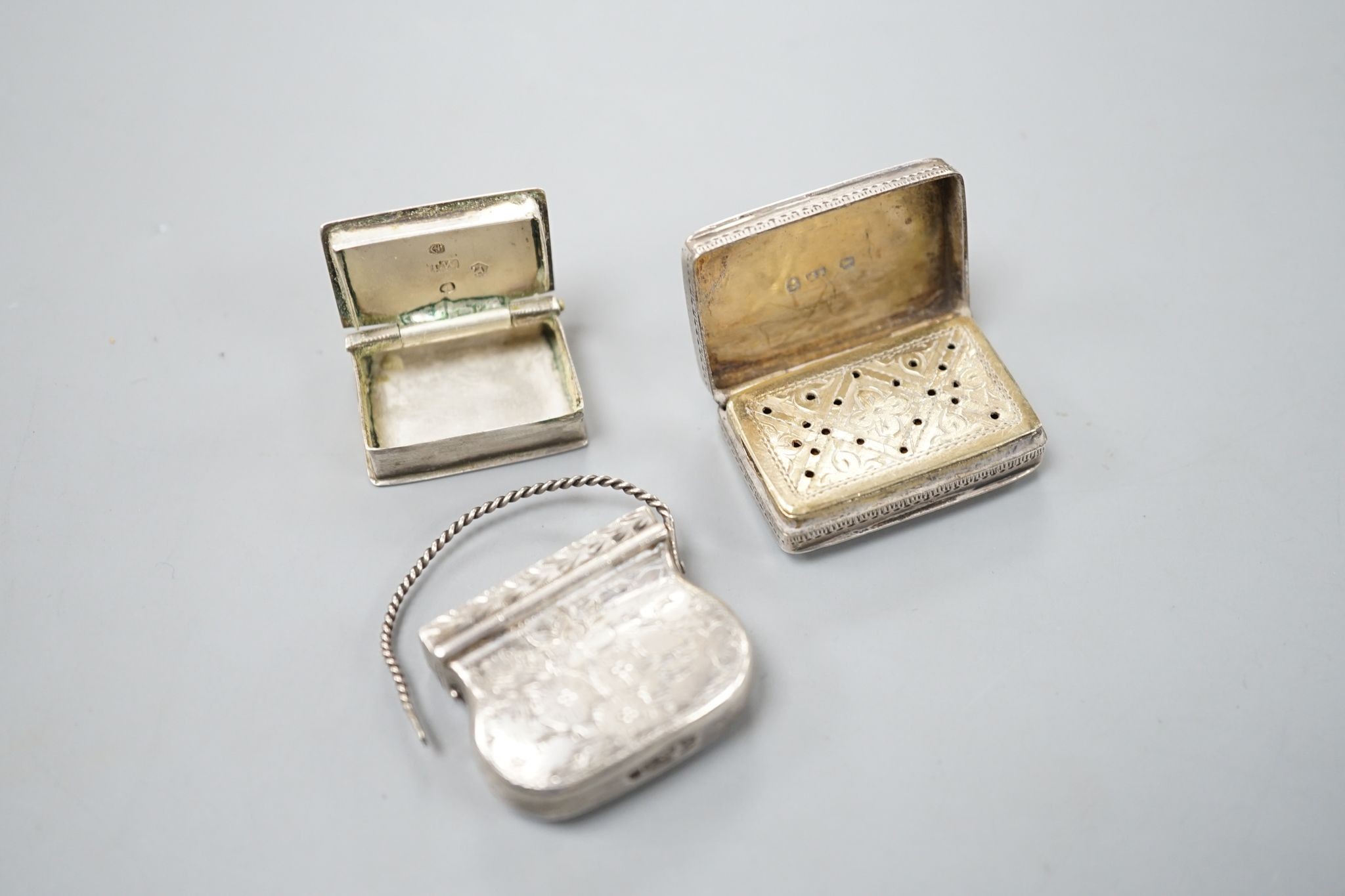 A George IV novelty silver vinaigrette, modelled as a handbag, Gervase Wheeler, Birmingham, 1832, 27mm(handle at one end detached), one other silver vinaigrette, Edward Smith, Birmingham, 1829 and a similar silver 'book'